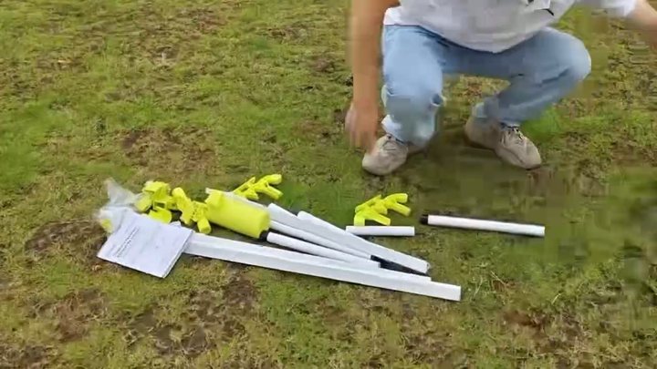 Square base rail, yellow connectors, round tubes, net assemblies, and accessories laid out on grass
