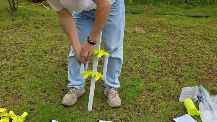 Two yellow center brackets and short round crossbars being installed on the square base rail